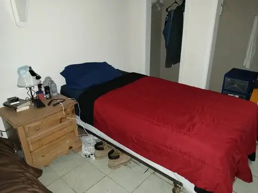Cozy bedroom with red bedding at LCRC, a sober living home in Houston.
